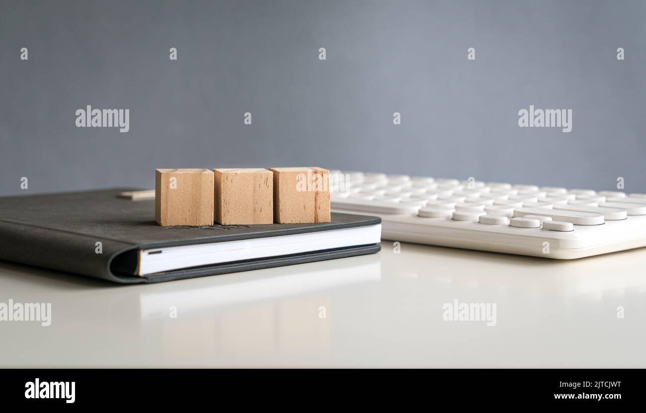 Three blank wooden block cubes in a row on top of a notepad next to