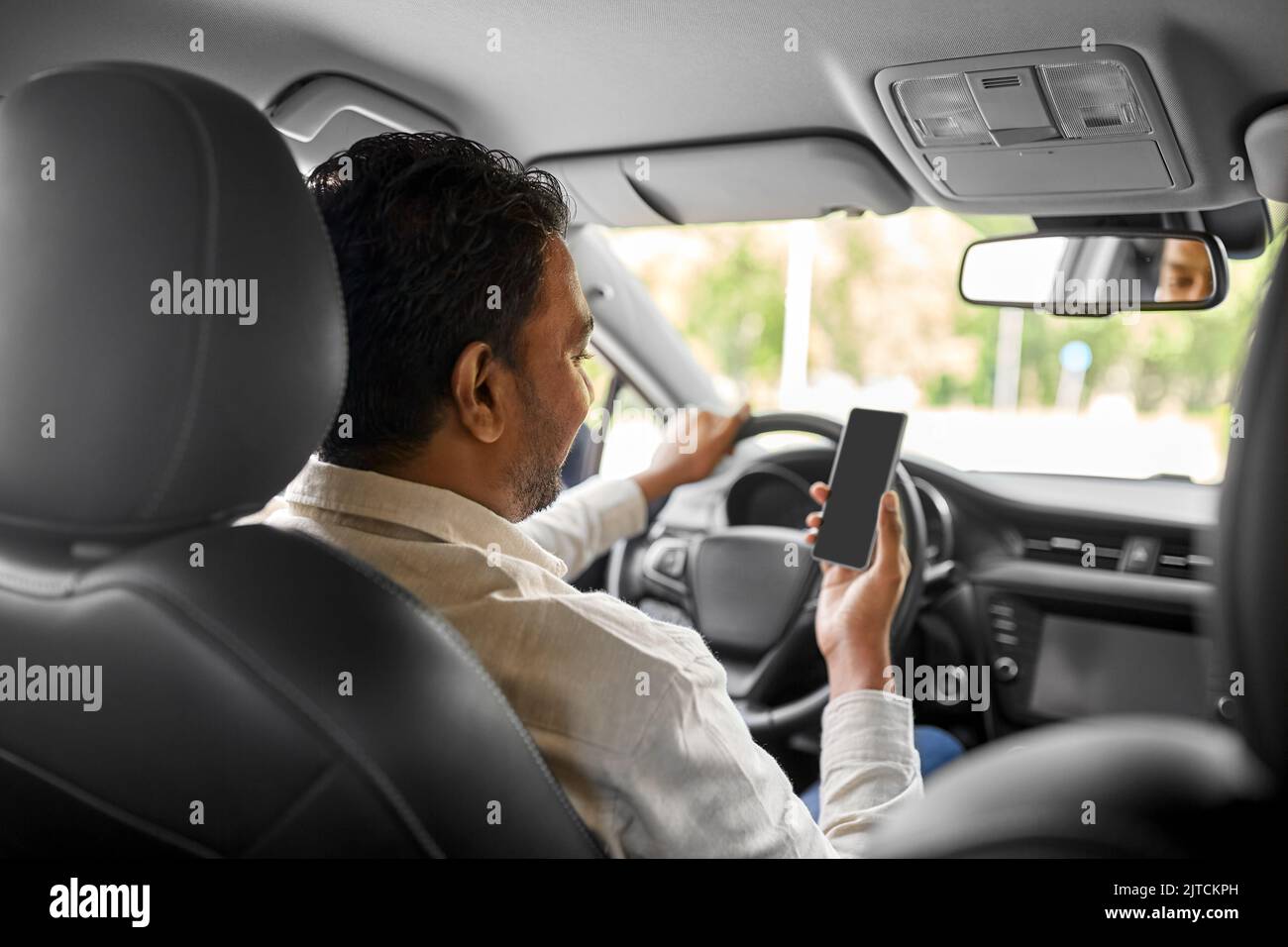 smiling indian man in car using smartphone Stock Photo