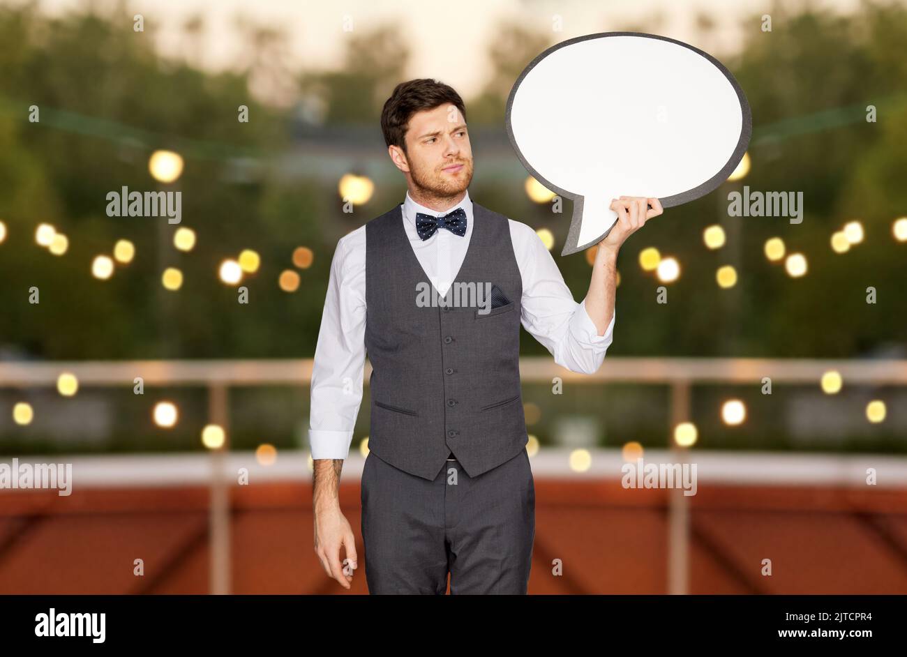 man in suit with text bubble at rooftop party Stock Photo