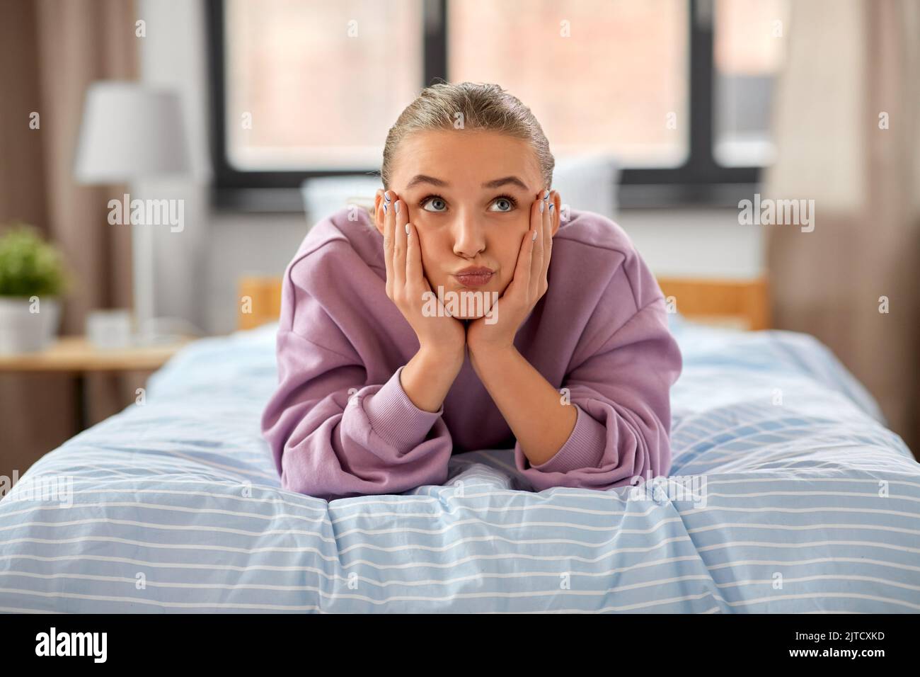 girl lying on bed at home and making face Stock Photo