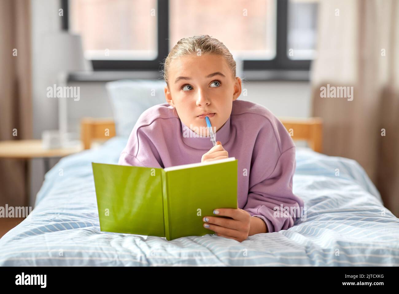 thinking girl with diary lying on bed at home Stock Photo
