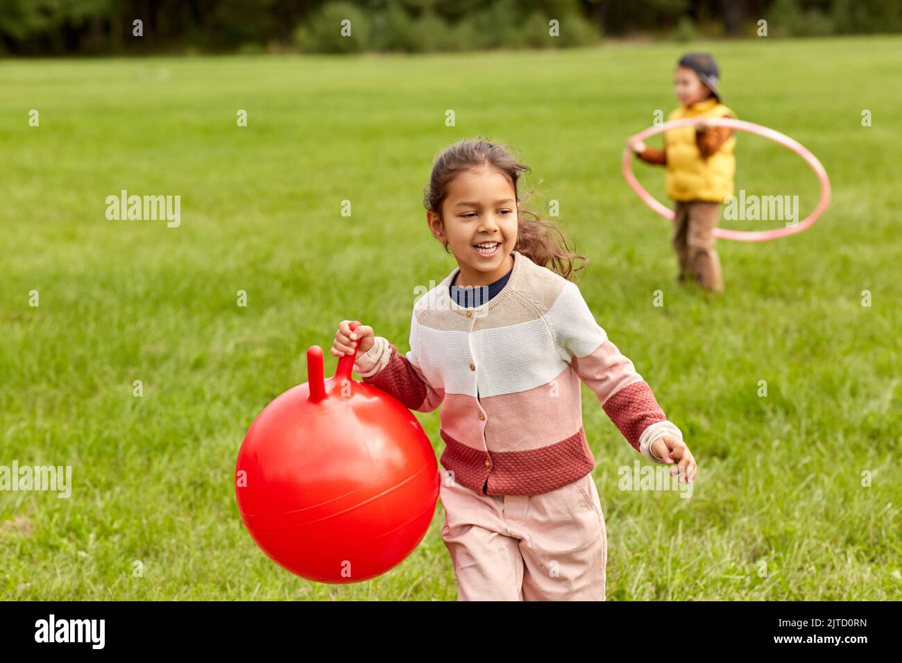 happy little girl playing with hopper ball at park Stock Photo Alamy