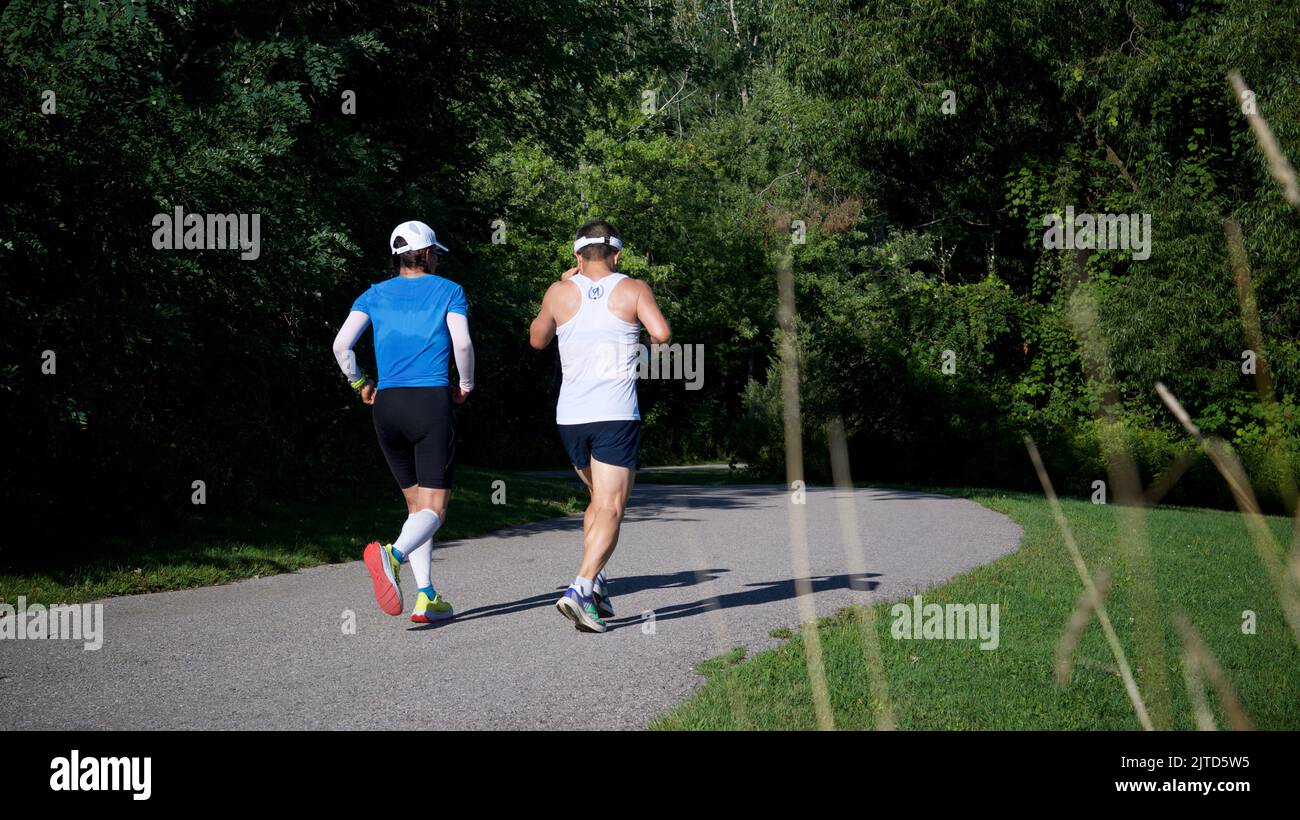 Toronto, Ontario / Canada - Aug 28, 2022: Two adult male jogging in the public park Stock Photo