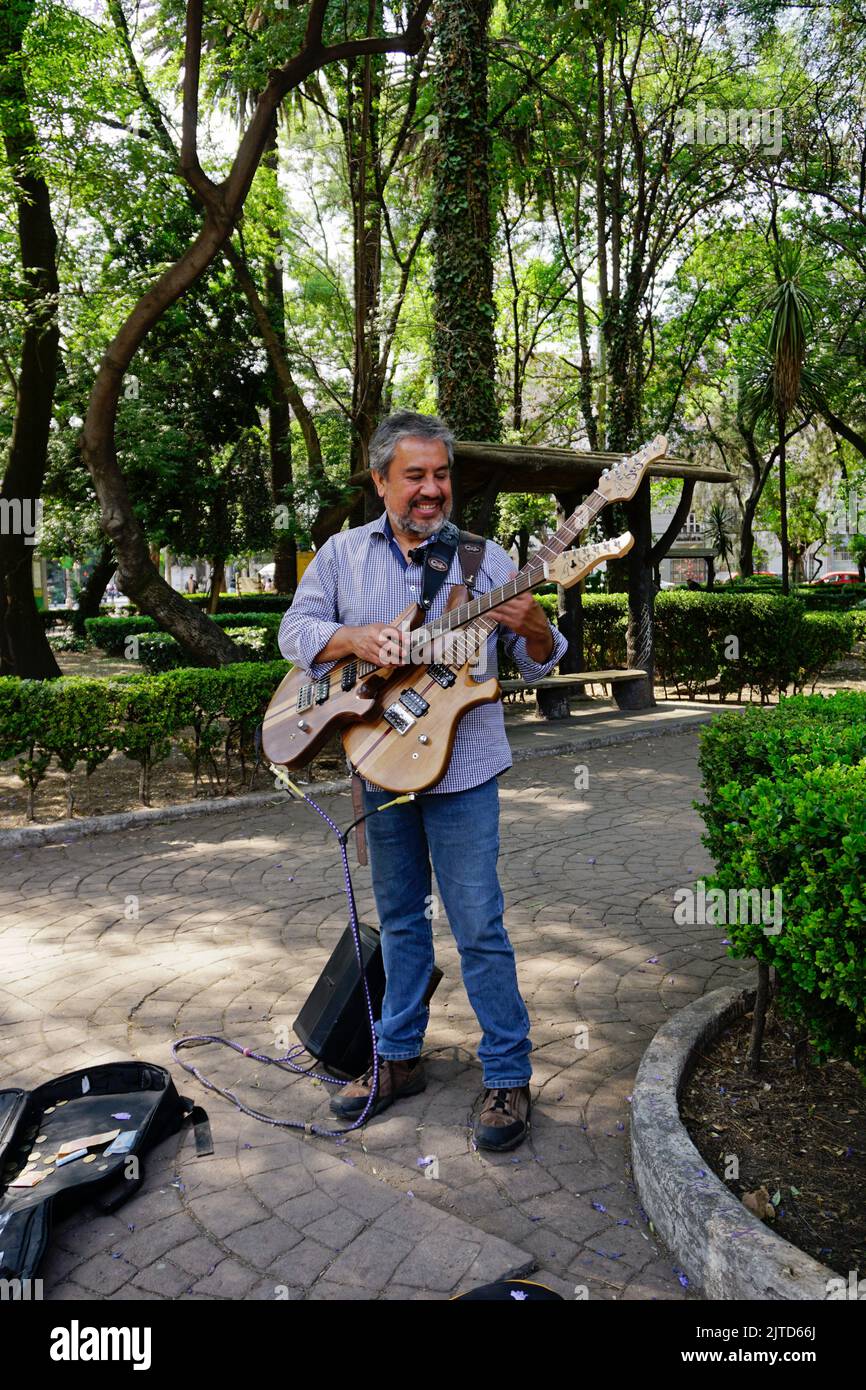 Hispanic man playing double guitars in Parque Mexico, Hipodromo neighborhood, in Cuauhtemoc area, Ciudad de Mexico, CDMX Stock Photo
