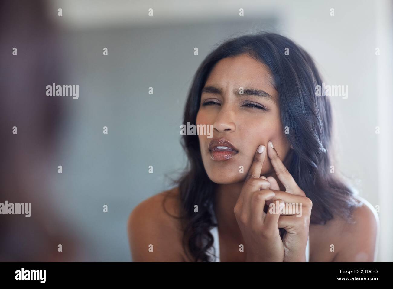 Why you do this to me a young woman squeezing a pimple in front of the