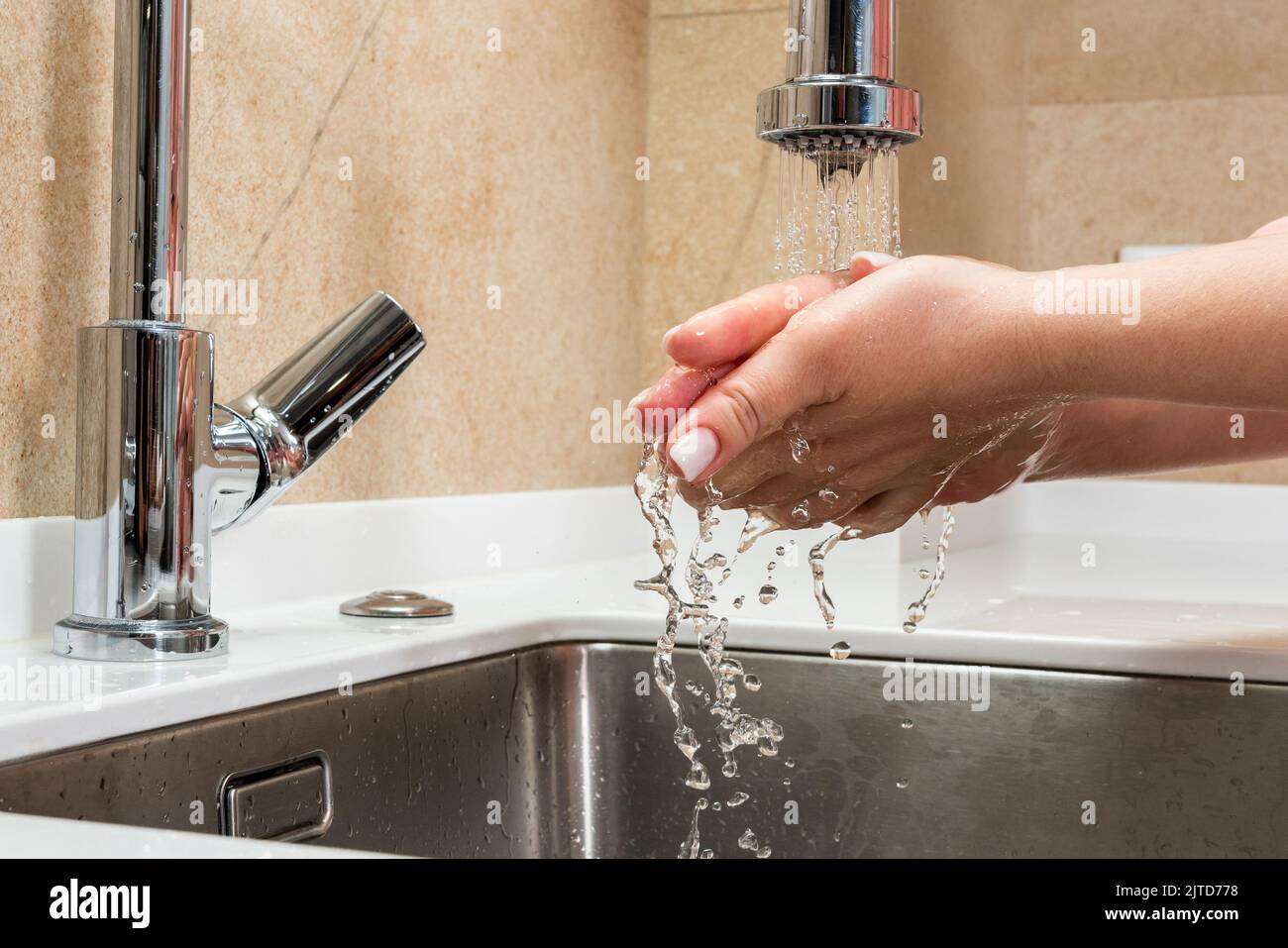 Girl washes her hands under drops of water over the sink Stock Photo