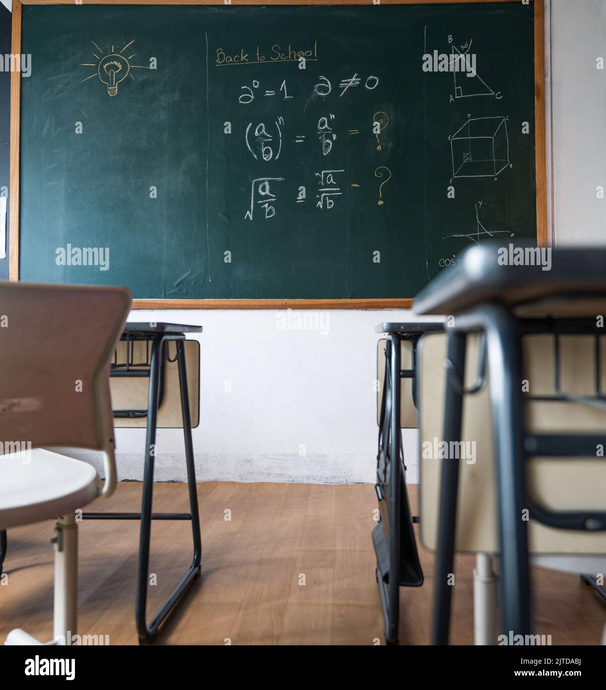 Empty classroom with chairs elementary school desks and chalkboard