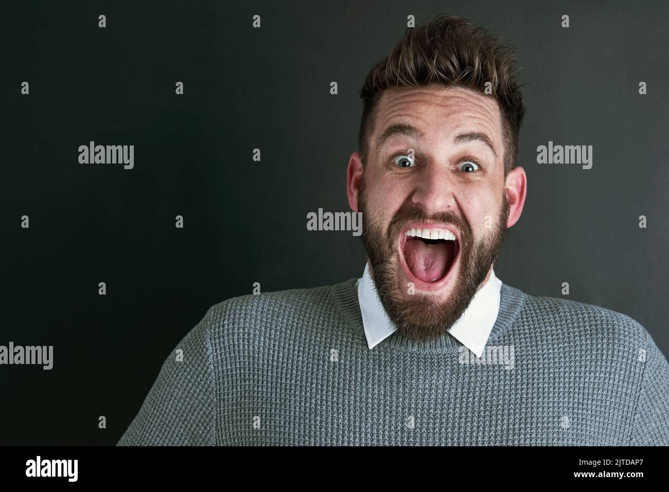 Unbelievable. Portrait of an ecstatic young man posing against a dark background in studio. Stock Photo