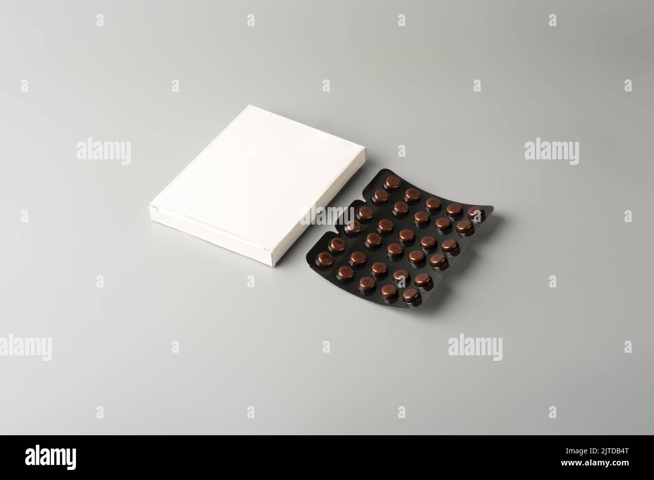 brown blister packs with pills and blank white box, dark color medical drugs vitamin, antibiotic, pain relievers, package for tablets isolated on gray Stock Photo