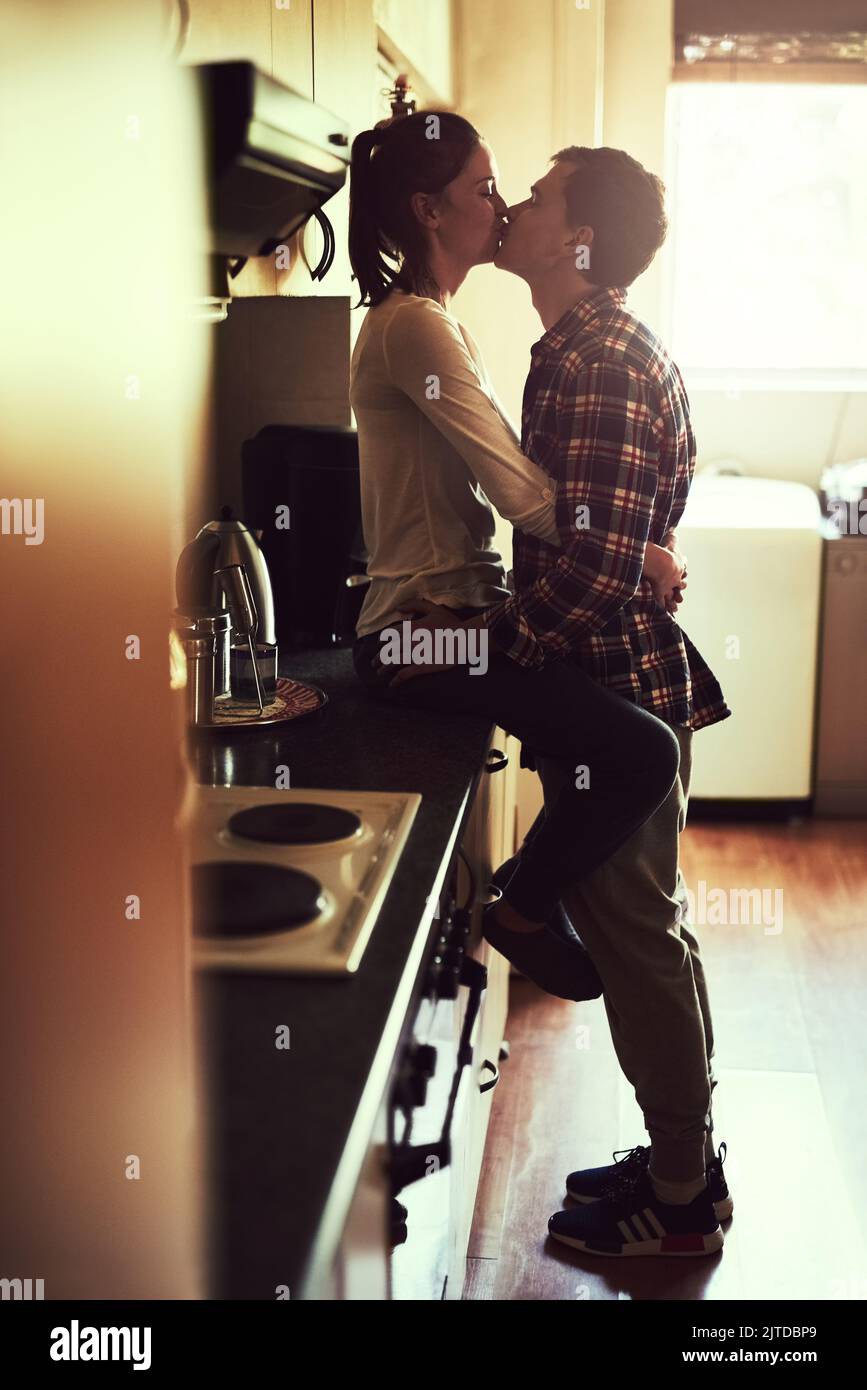 The world stops turning when they kiss. an affectionate young couple sharing a romantic kiss in the kitchen. Stock Photo