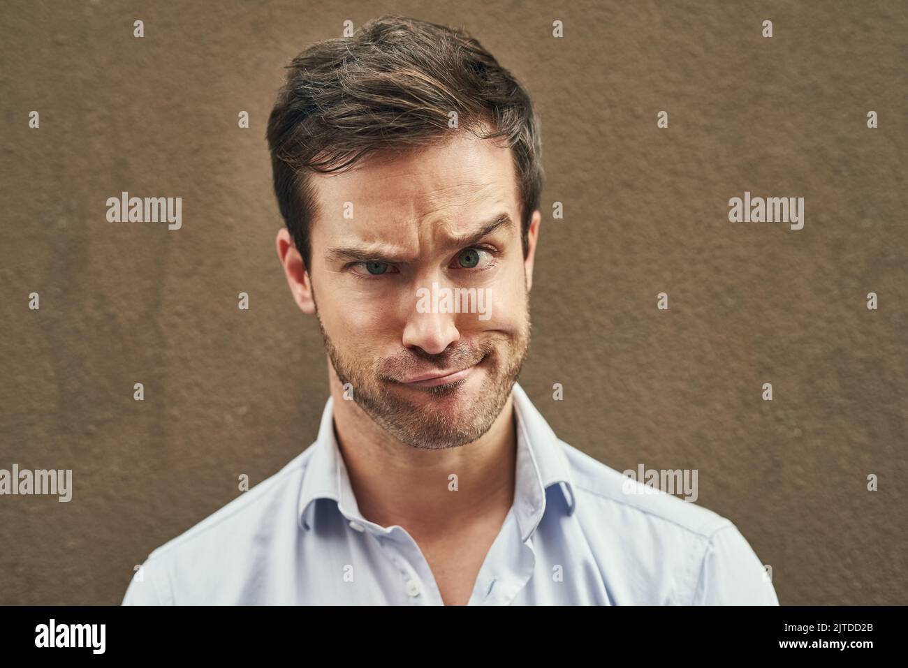 Goofing around. Portrait of a young man pulling a funny face against a dark background. Stock Photo