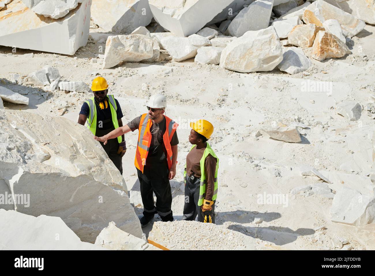 Group of intercultural workers of quarry checking quality of marble ...