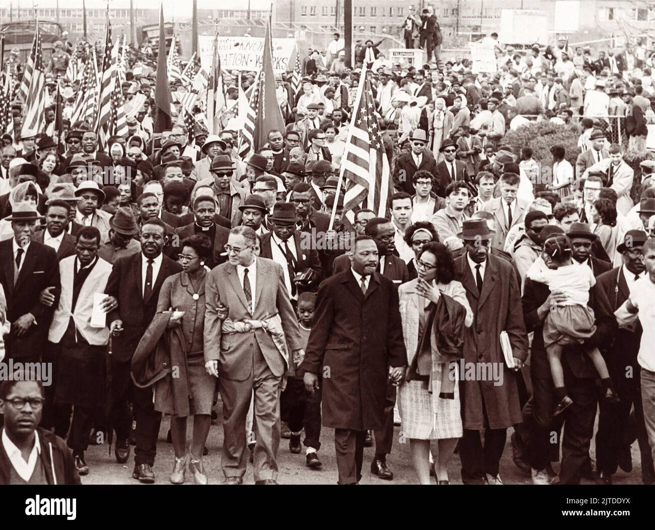 Martin Luther King, Jr. leads nonviolent demonstrators into Montgomery, Alabama, toward the steps of the Alabama State Capitol Building on March 25, 1965, the final day of the Selma to Montgomery Marches. Pictured in the front row line (from L to R) are A. Philip Randolph, John Lewis, Ralph Abernathy, Ruth Harris Bunch, Ralph Bunch, Martin Luther King, Coretta Scott King, Fred Shuttlesworth, and Hosea Williams (holding girl.) Stock Photo