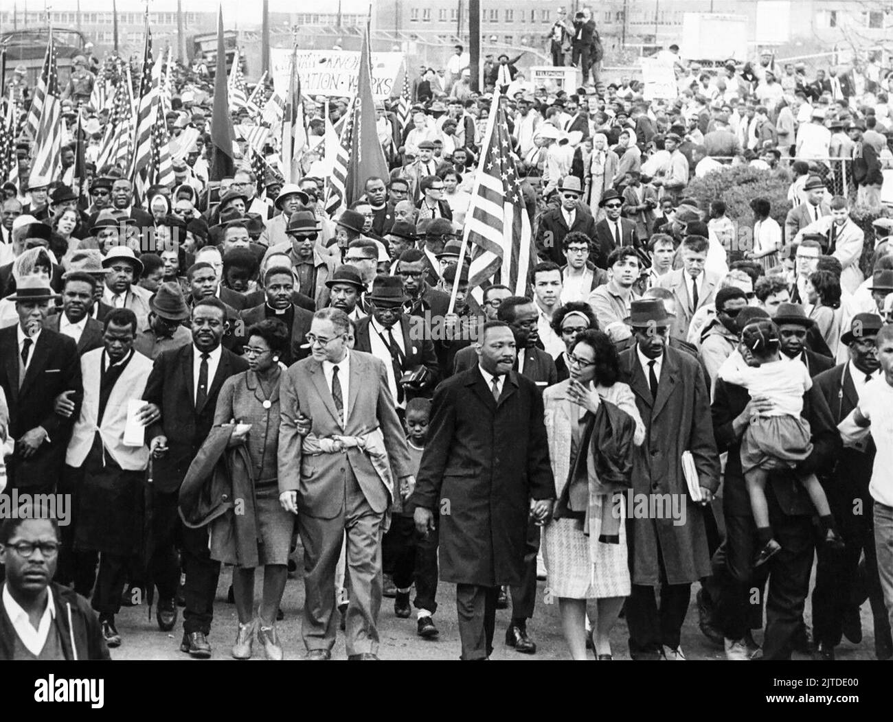 Martin Luther King, Jr. leads nonviolent demonstrators into Montgomery, Alabama, toward the steps of the Alabama State Capitol Building on March 25, 1965, the final day of the Selma to Montgomery Marches. Pictured in the front row line (from L to R) are A. Philip Randolph, John Lewis, Ralph Abernathy, Ruth Harris Bunch, Ralph Bunch, Martin Luther King, Coretta Scott King, Fred Shuttlesworth, and Hosea Williams (holding girl.) Stock Photo