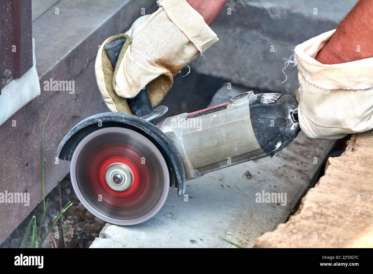 A worker with a circular saw cuts a concrete block in close-up. Stock Photo
