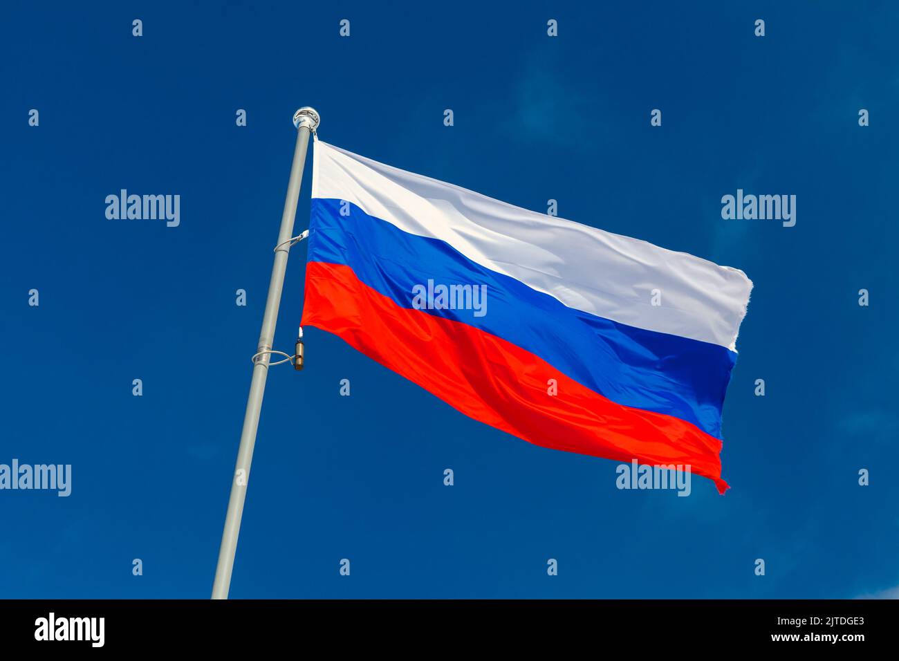 The national flag of Russia, the State Flag of the Russian Federation is on a flagpole under blue sky on a sunny day Stock Photo