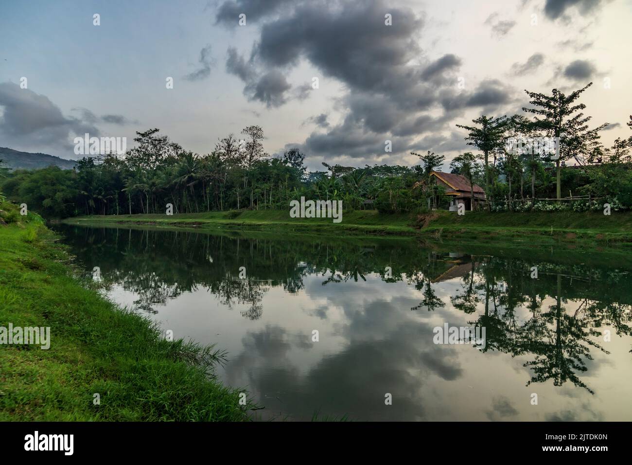 Colorful sunset, sunrise over a wide river. Twilight rays and clouds reflected in the calm water in Trenggalek village, East Java, Indonesia Stock Photo