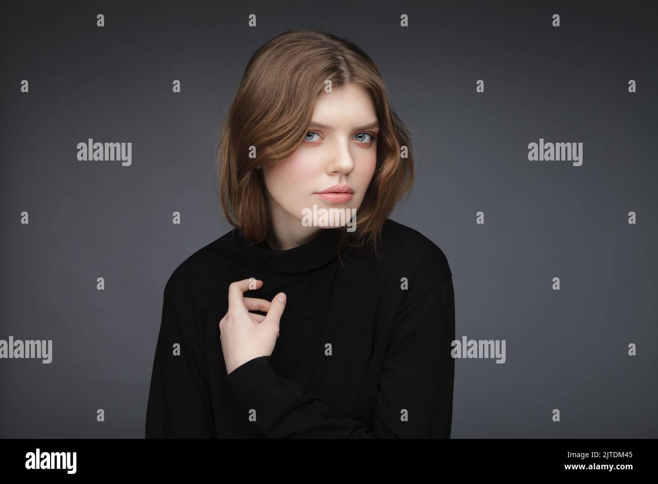 One young woman studio portrait wearing black turtleneck shirt. Image of young charming girl. Stock Photo