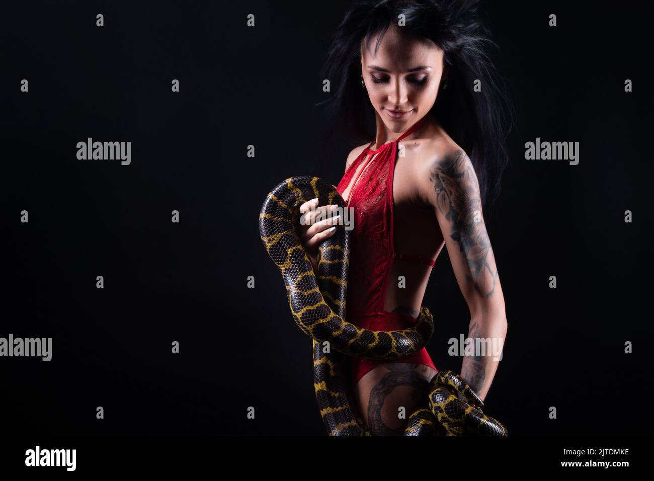 Photo of brunette woman with blowing hair holding snake Stock Photo
