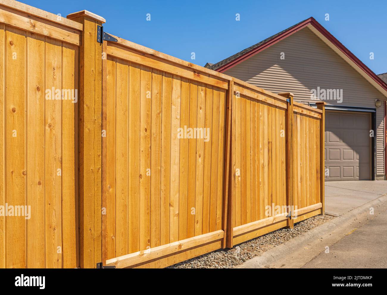 Nice new wooden fence around house. Wooden fence with lawn. Street