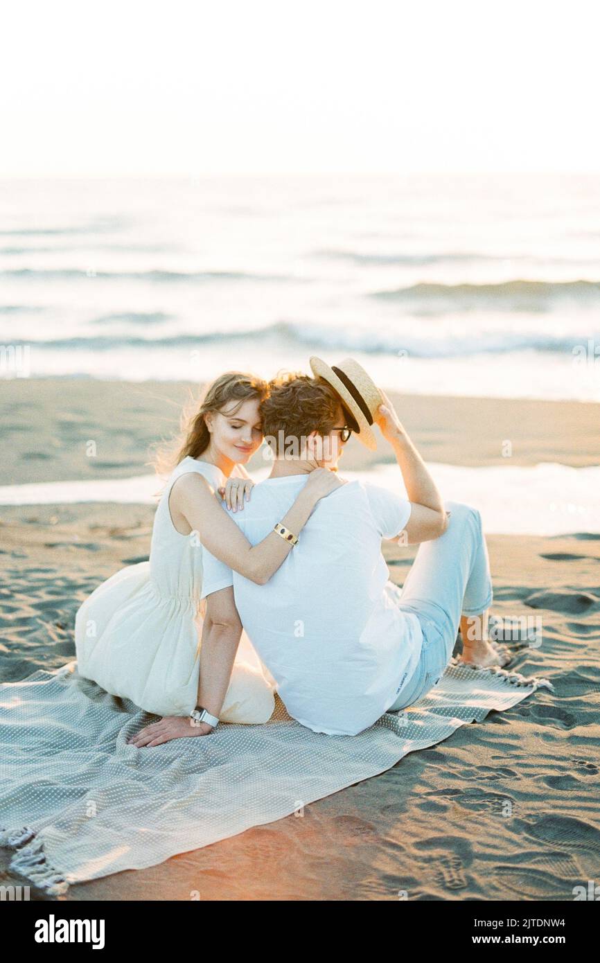 Woman hugging man shoulder while sitting on the beach Stock Photo - Alamy