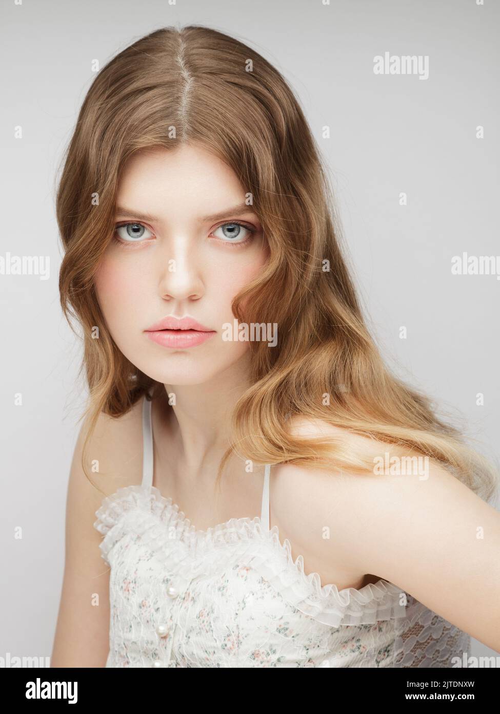 One young woman looking at camera. Vertical studio portrait of young charming girl. Stock Photo