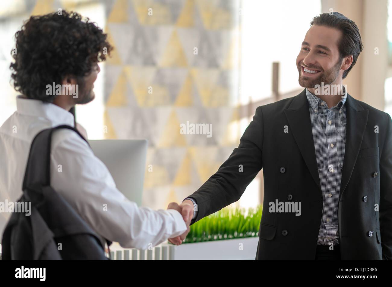 Young manager welcoming new employee and looking positive Stock Photo