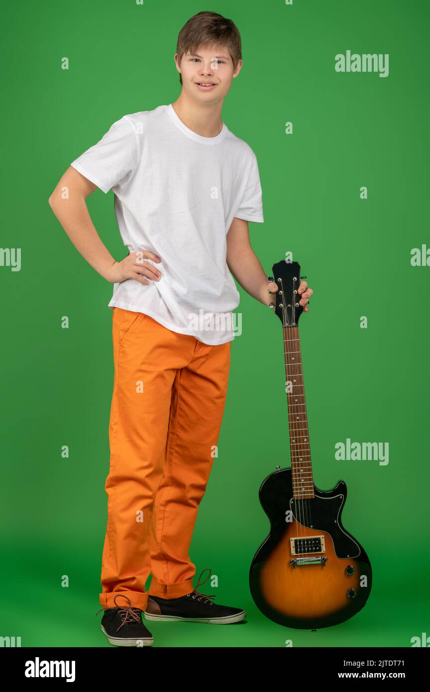 A boy in orange pants with a guitar looking happy Stock Photo