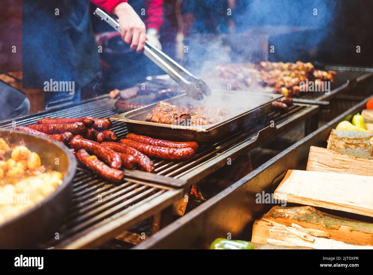 Outdoor street food festival. Chief cooking sausages, meat and potatoes