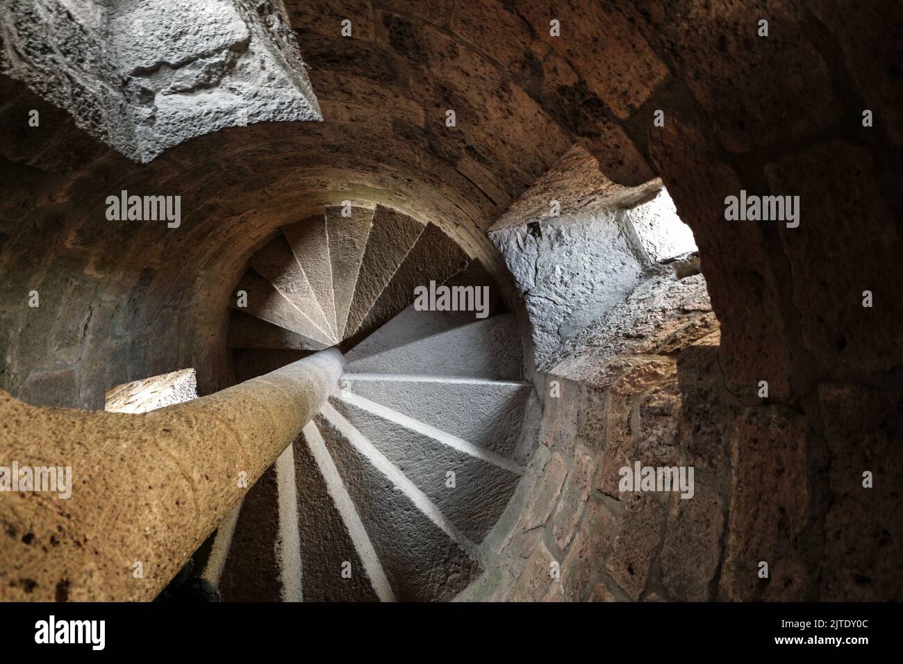 Spiral Stone Staircase Illuminated by Light Spilling through Windows, France Stock Photo