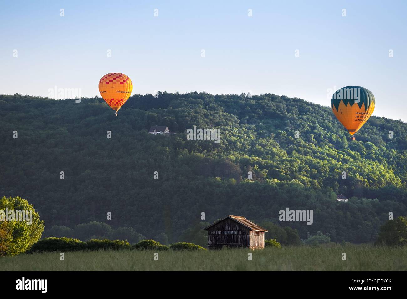 Hot Air Balloons Illuminated by Late Evening Light near the Village of La Roque-Gageac, Dordogne, Aquitaine, France, EU. Stock Photo