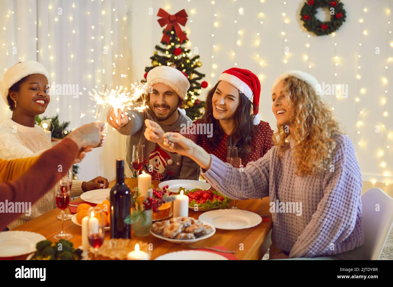 Happy diverse friends celebrate Christmas light fireworks Stock Photo