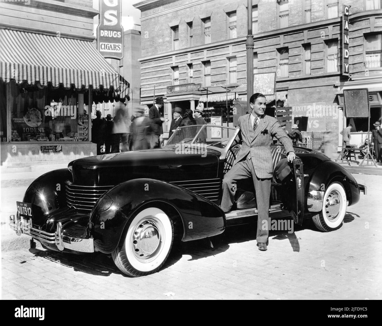 TYRONE POWER in poses with 1936 Auburn Cord 810 Phaeton automobile / car on set candid publicity for Twentieth Century Fox Stock Photo