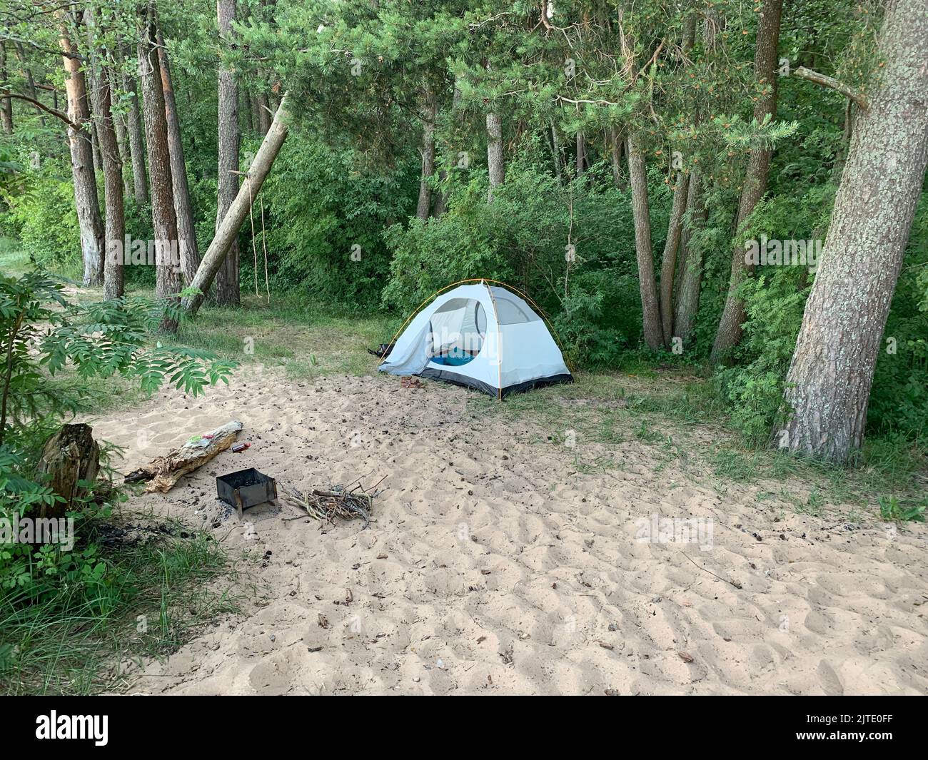 The tent stands in the forest next to the barbecue Stock Photo