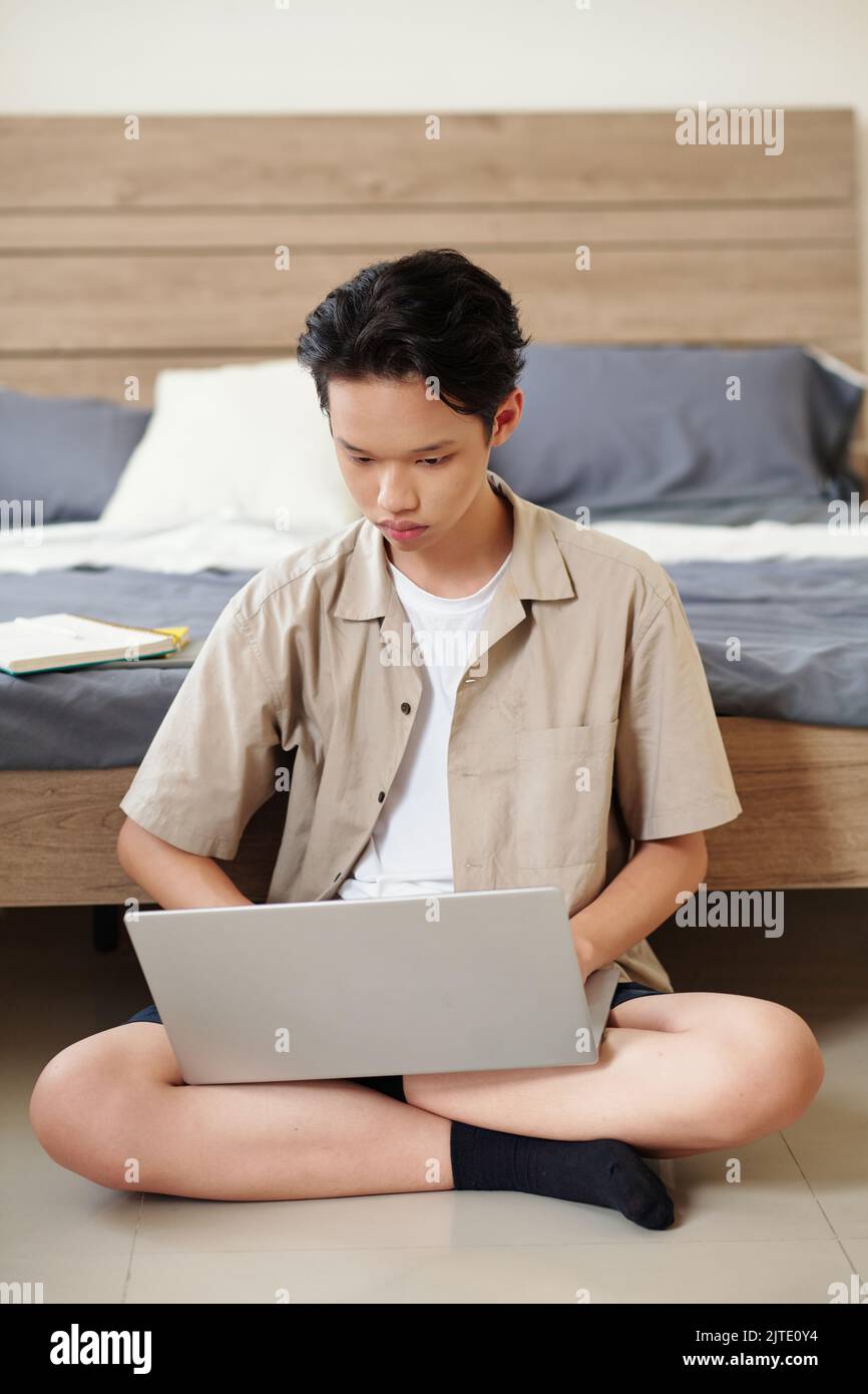 Concentrated teenage boy checking programming code on laptop screen ...