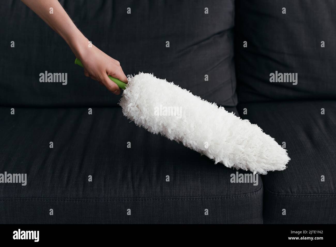 partial view of woman cleaning couch with dust brush Stock Photo