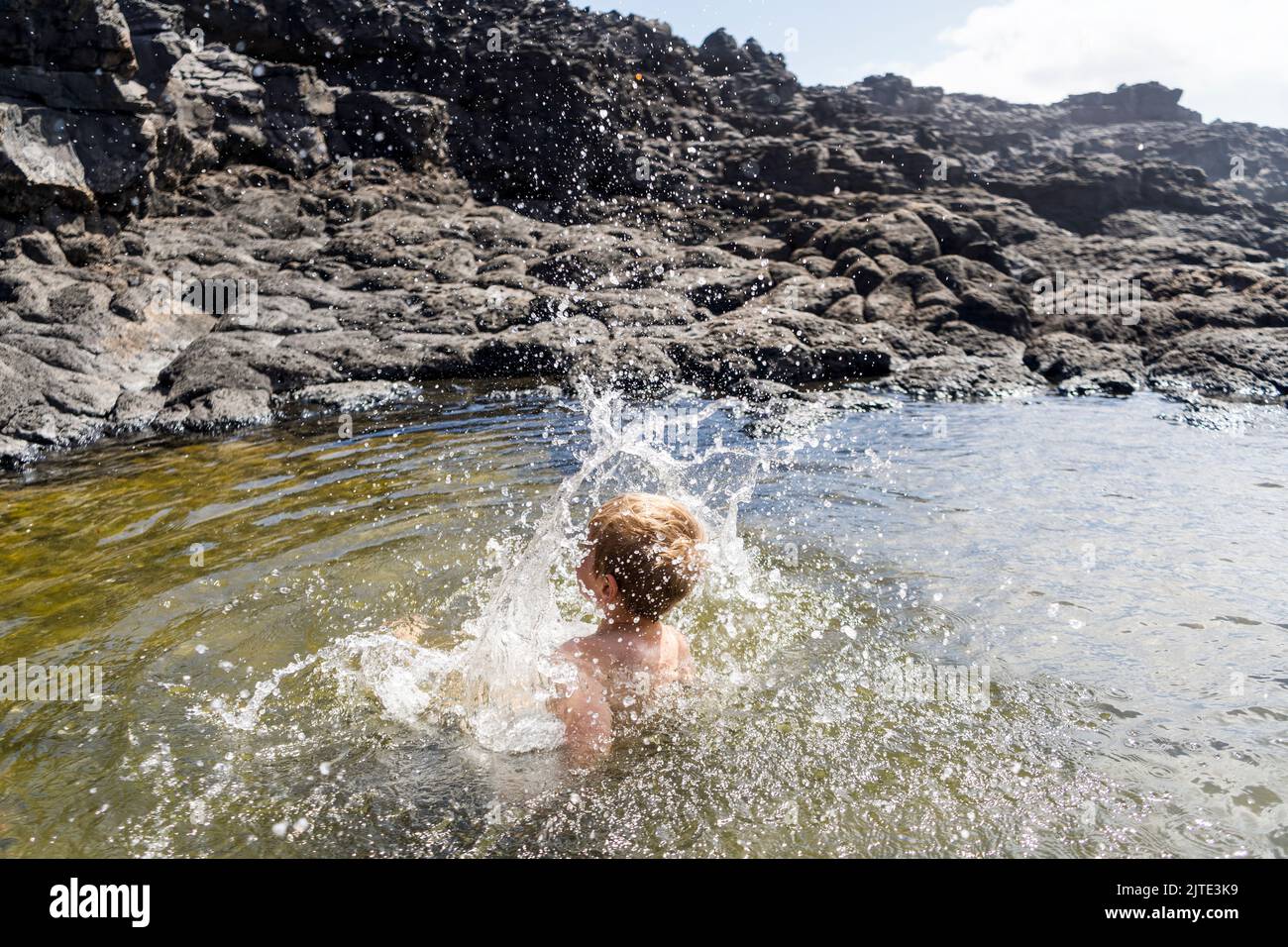 Small boy cheerfully jumping in Charcones natural pools in Lanzarote, Canary Islands, Spain Stock Photo