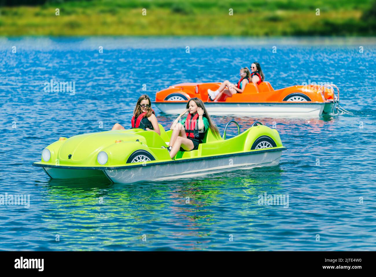 Two pedal boats on a mountain lake with teenagers Stock Photo