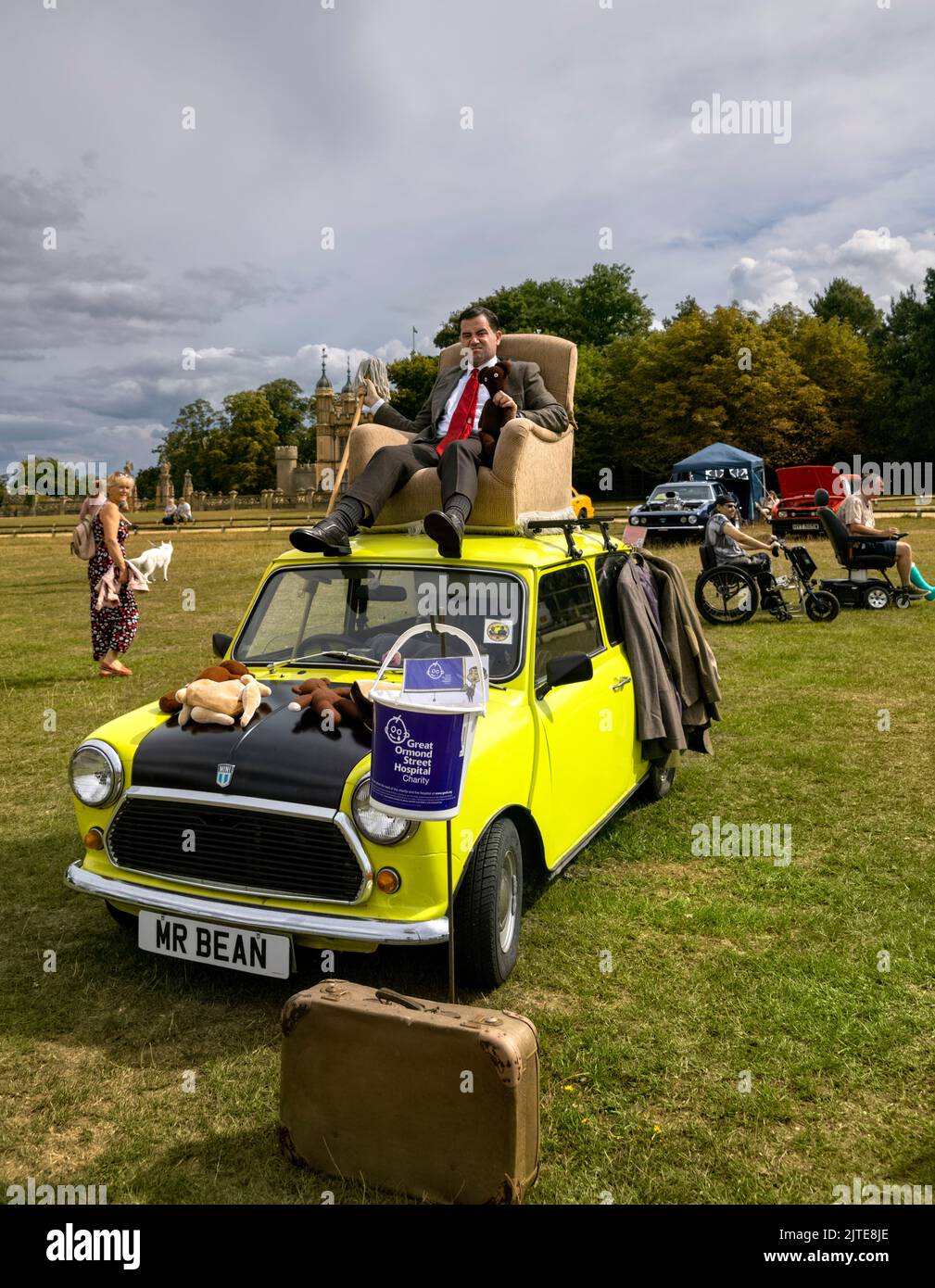 Mr. Bean lookalike sitting in an armchair on top of yellow mini classic car at Knebworth House Classic Car Show 2022 raising money for charity Stock Photo