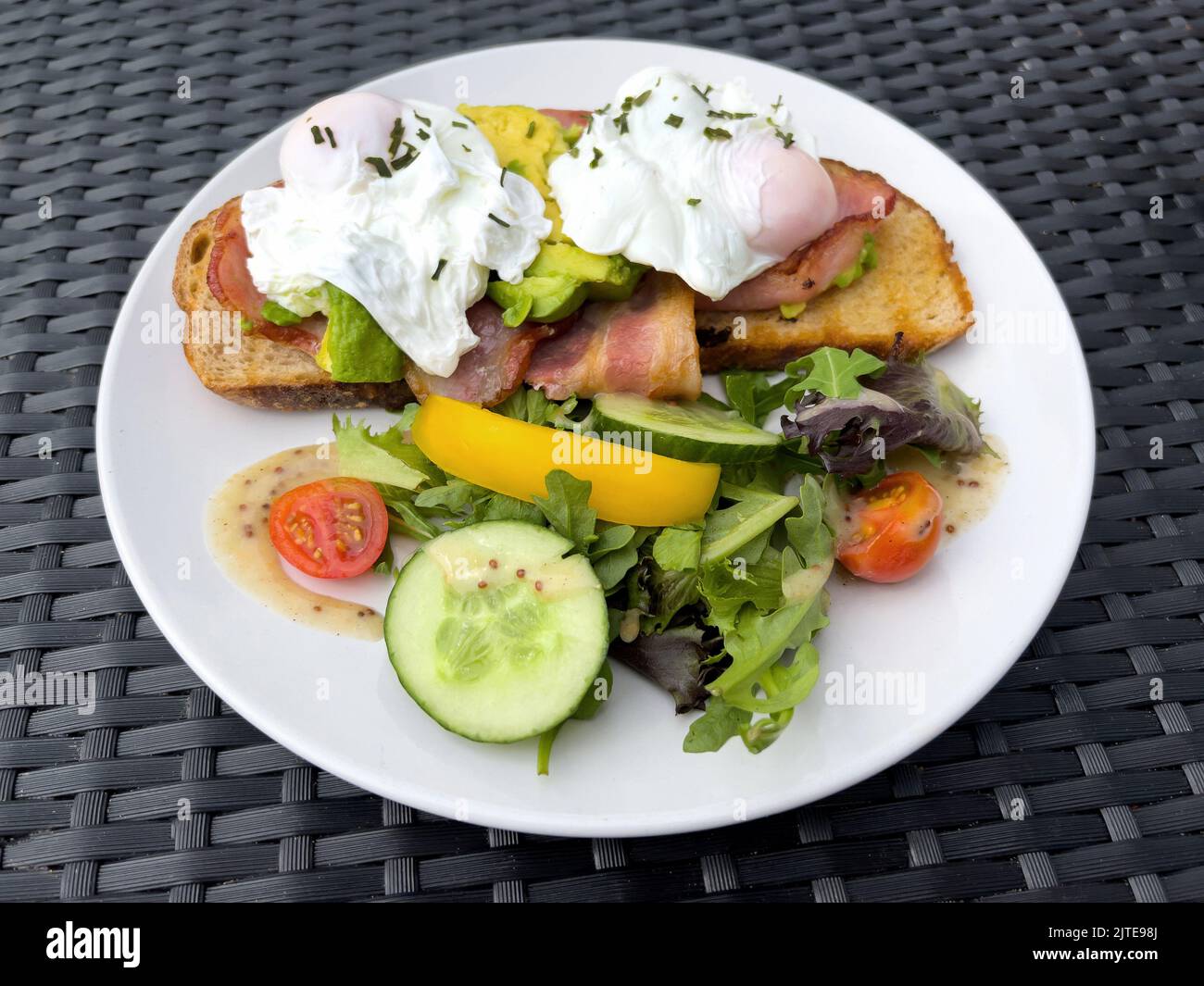 Healthy breakfast with poached eggs, grilled bacon, and avocado served on a slice of toasted sourdough bread Stock Photo