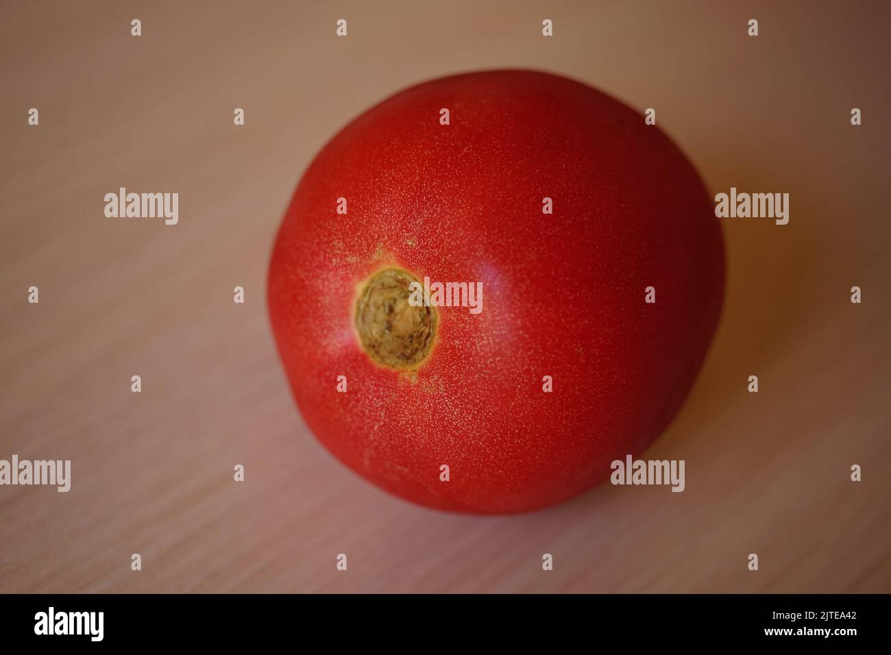 Ripe red tomato on pale wooden table. Stock Photo