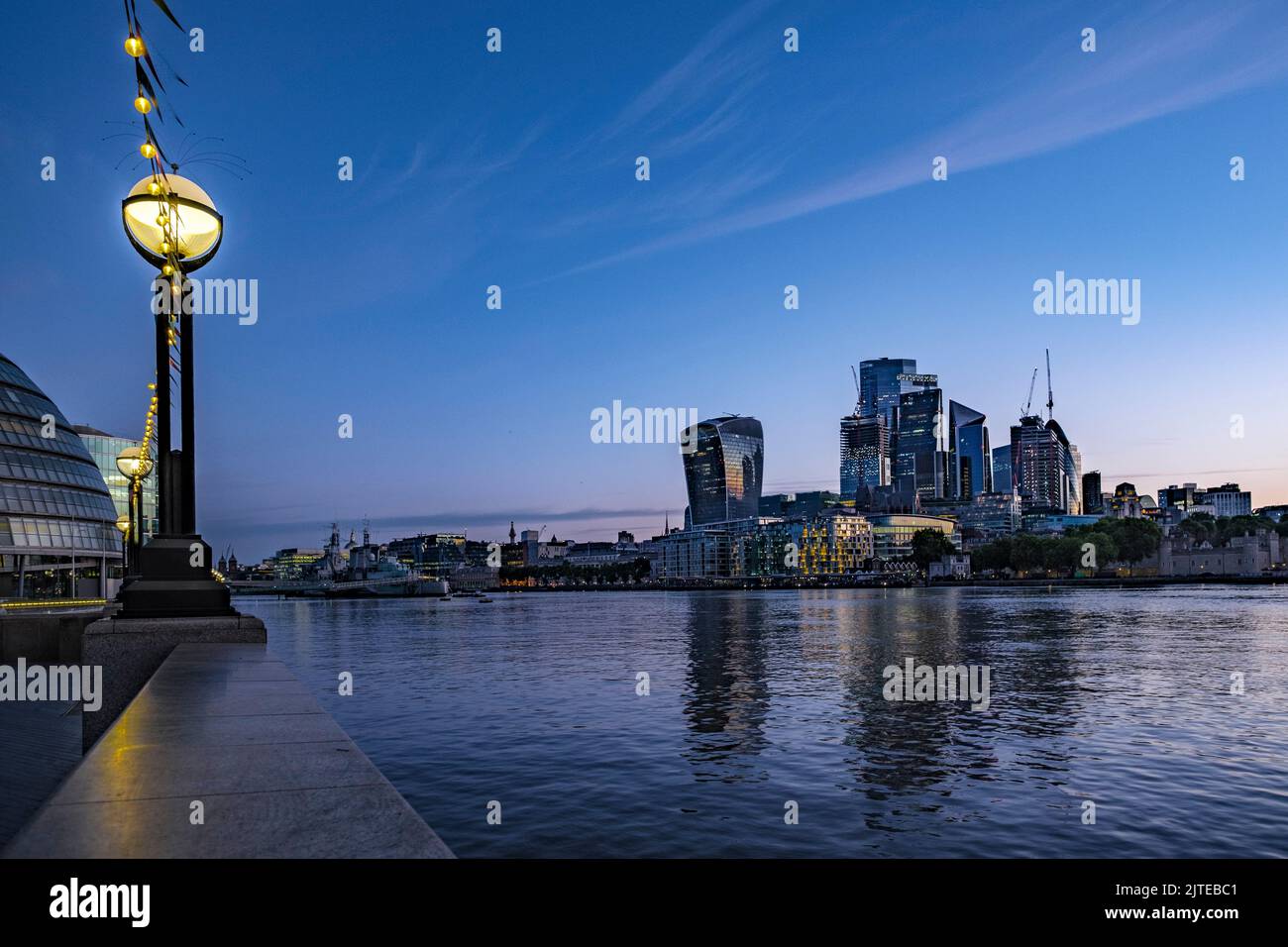 Low wide angle shot of HMS Belfast and The City of London at dawn with the Thames in front Stock Photo