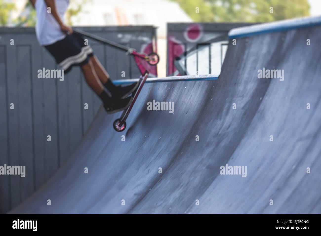 Skate park view with kids on a kick scooter doing tricks and stunts ...