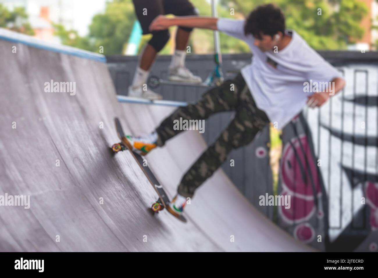 Skate park view with kids on a kick scooter doing tricks and stunts ...