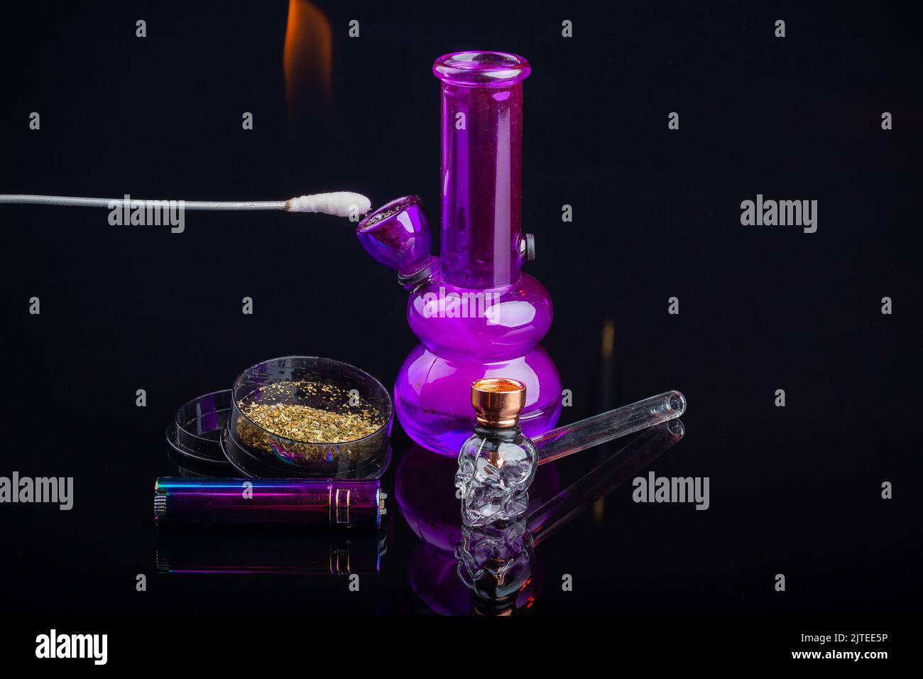 Closeup of ear stick lighting up weed in the purple glass bong