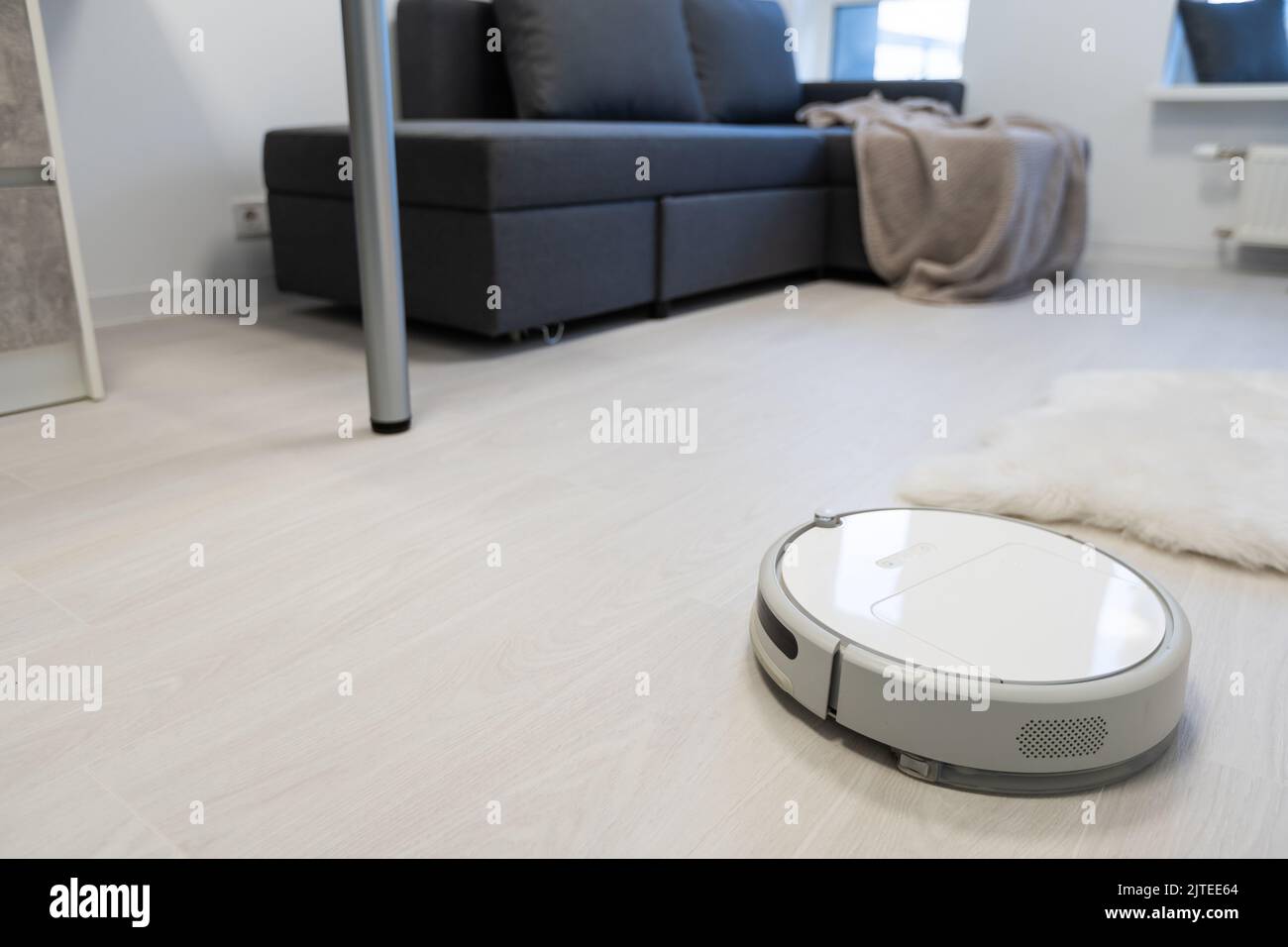 Smart House. Vacuum cleaner robot runs on wood floor in a living room ...
