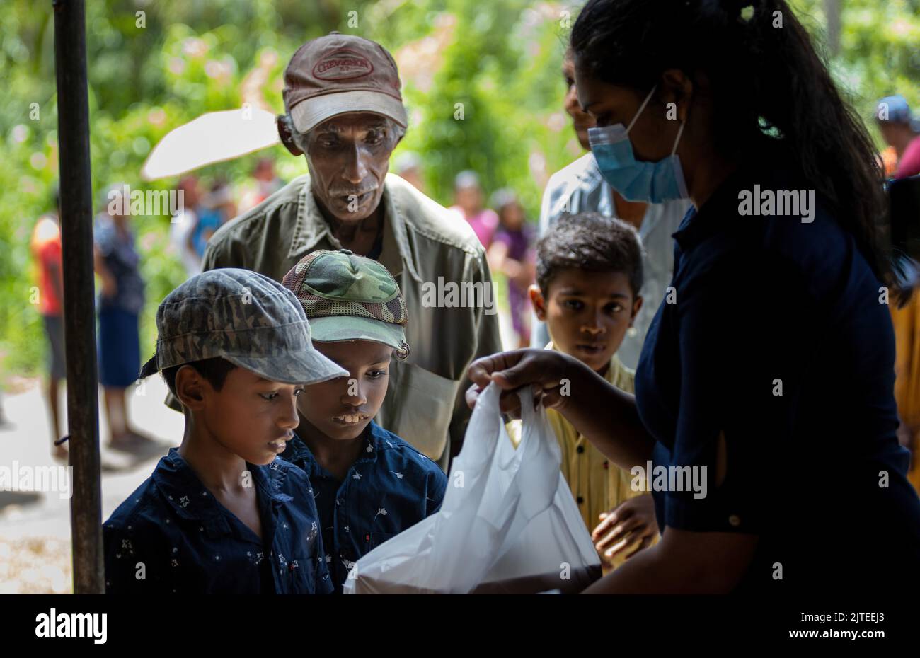 Child waiting to receive food parcel from a community almsgiving eagerly peeping: Galle, Sri Lanka 30th July 2022 Stock Photo