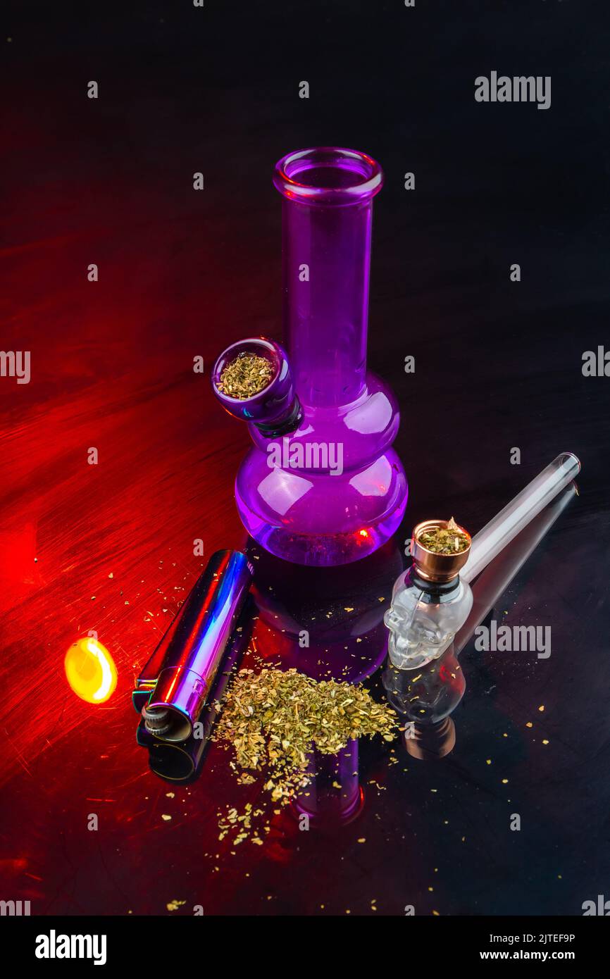 Vertical shot of bong and pipe filled with weed. Set of accessories for