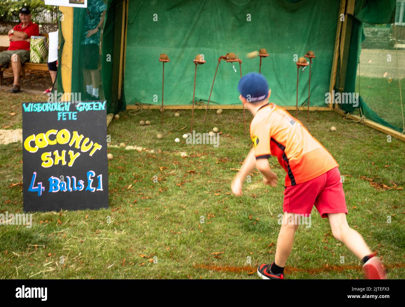 A young boy throws a wooden ball at coconuts at a traditional coconut