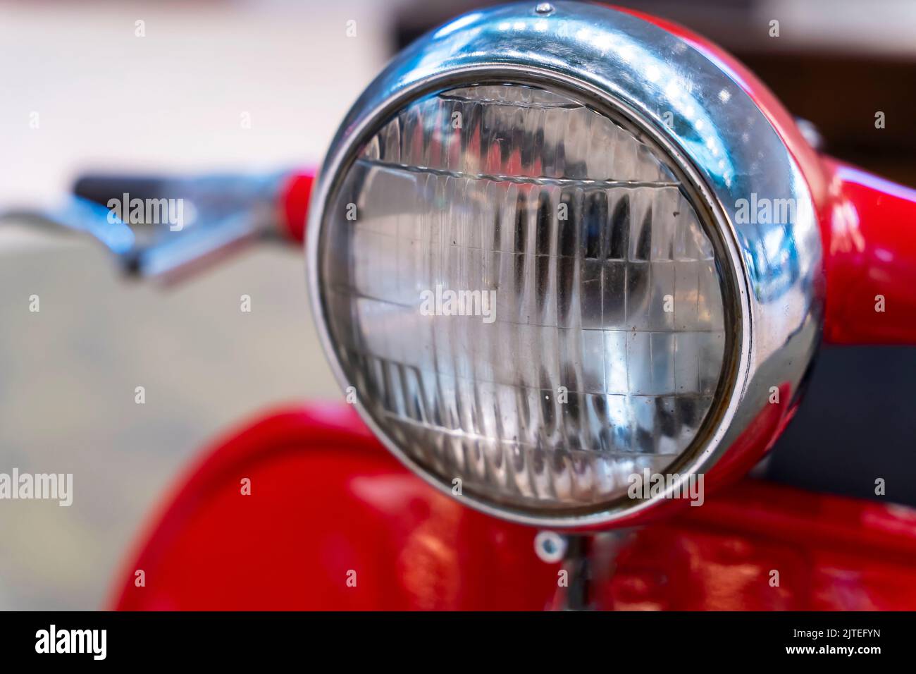 headlight, handlebar and control levers of a vintage red scooter. Stock Photo